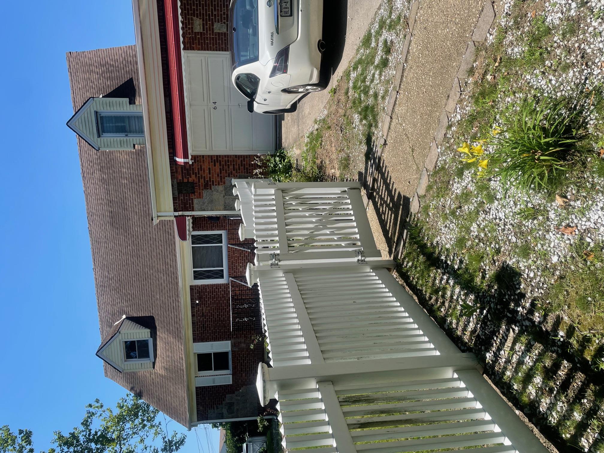 Cape cod-style house with an attached garage, brick siding, concrete driveway, and a gate