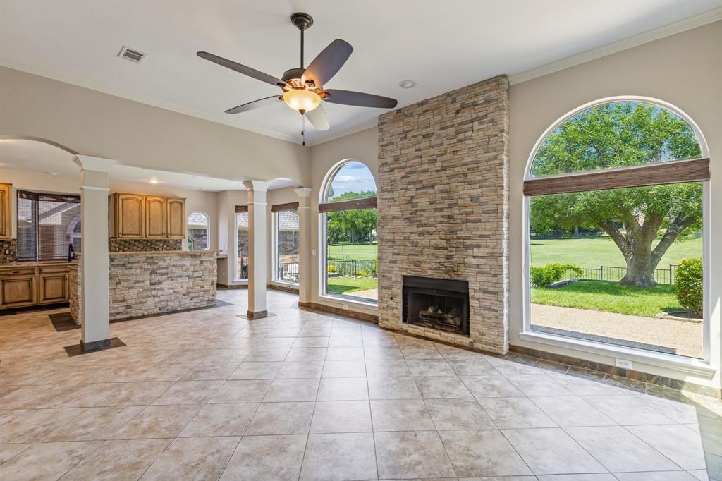 2925 Sunset Ridge McKinney, TX 75072 - Photo 8 of 33 Stunning family room featuring soaring ceilings, a dramatic floor-to-ceiling stone fireplace, and expansive windows that showcase breathtaking golf course and backyard views.