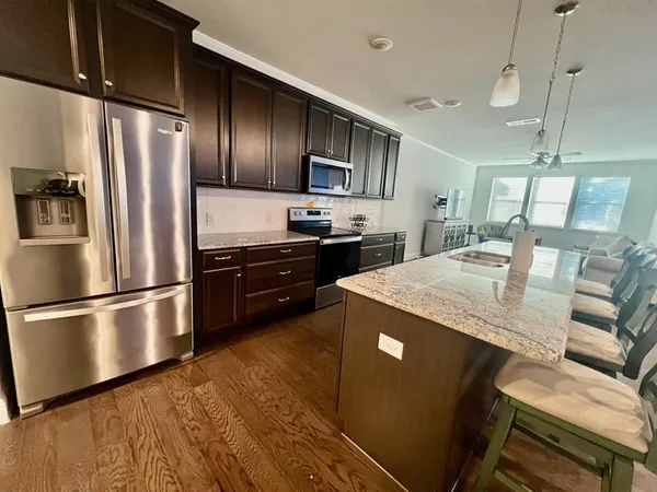 a kitchen with stainless steel appliances granite countertop a refrigerator a sink dishwasher a stove and a refrigerator