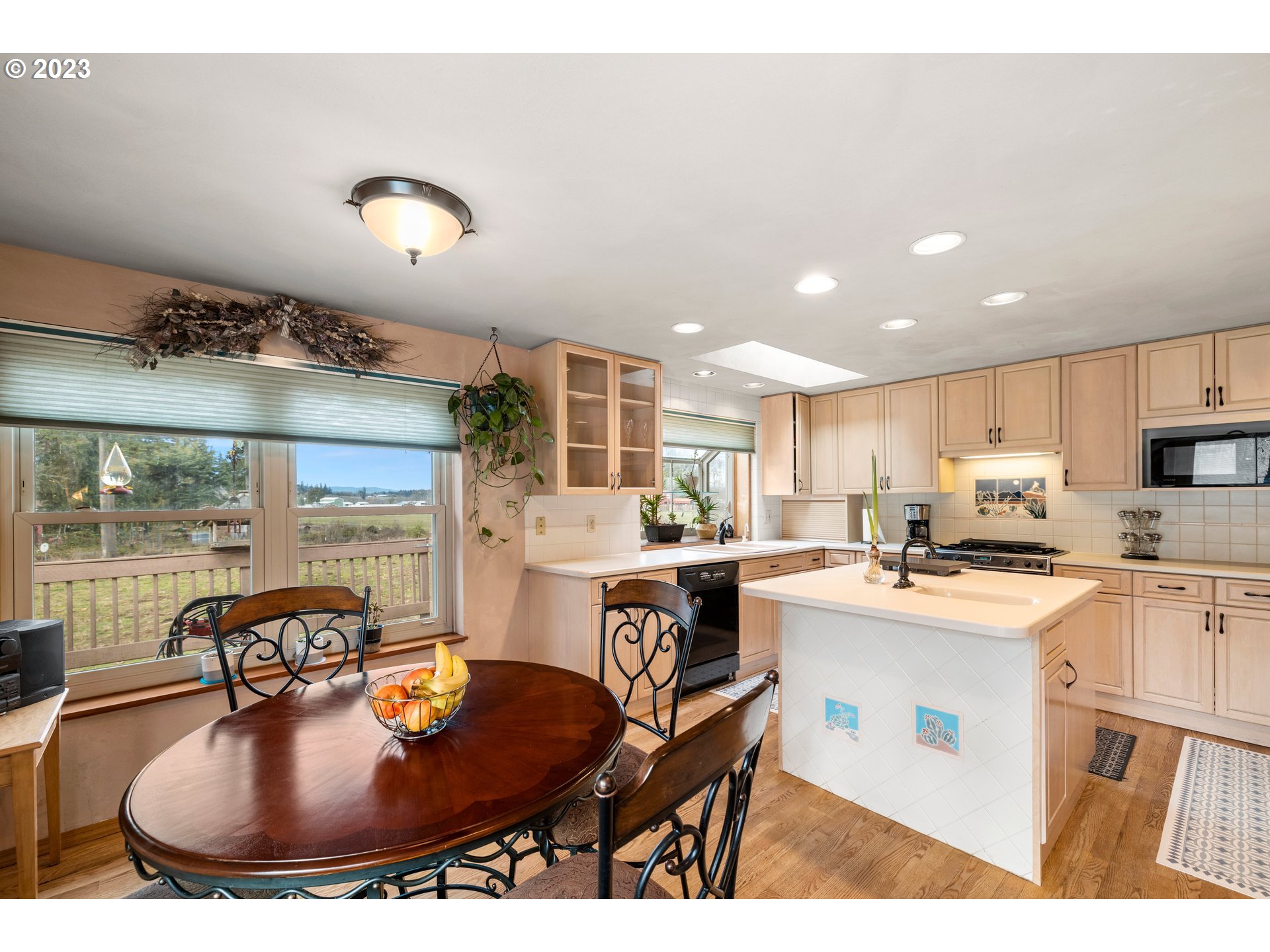 8880 Southwest River Road Hillsboro, OR 97123 - Photo 6 of 25 a kitchen with a stove a sink a kitchen island with a dining table and chairs