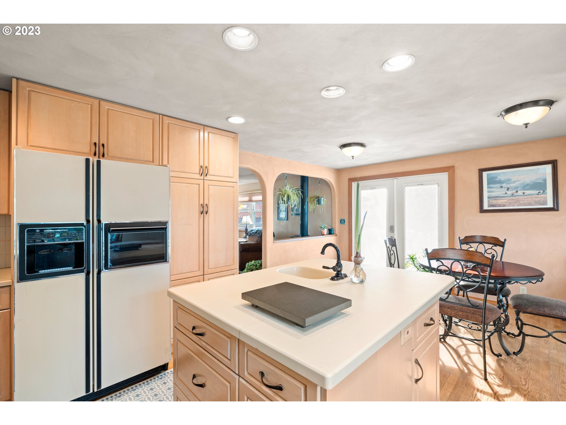 8880 Southwest River Road Hillsboro, OR 97123 - Photo 8 of 25 a kitchen with stainless steel appliances a refrigerator a stove a dining table and chairs with wooden floor
