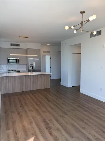 a view of kitchen and empty room with wooden floor