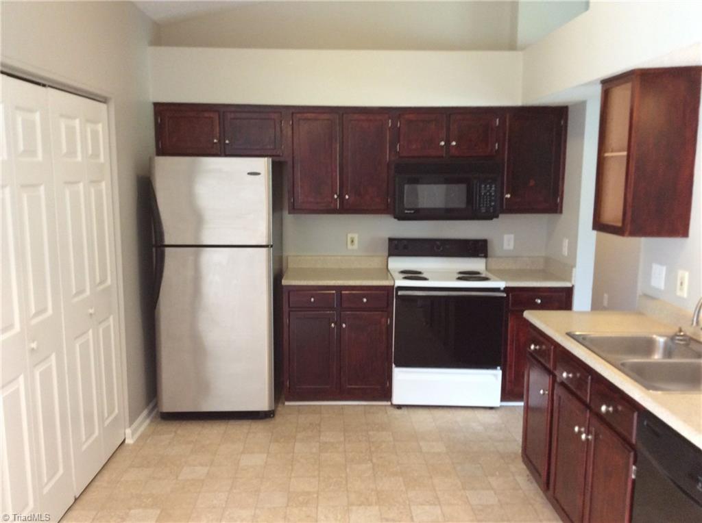 Here in the kitchen we can see the new vinyl flooring, the fresh new paint, the cathedral ceiling, the stove, refrigerator and built-in microwave. The double doors on the left are for the laundry area. Dishwasher is located at the bottom right side of this photo.