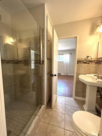 a bathroom with a sink a toilet a mirror and shower
