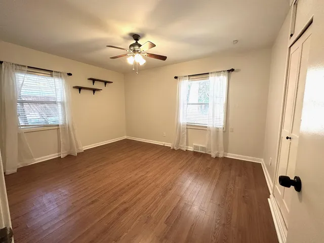 a view of an empty room with a window and wooden floor
