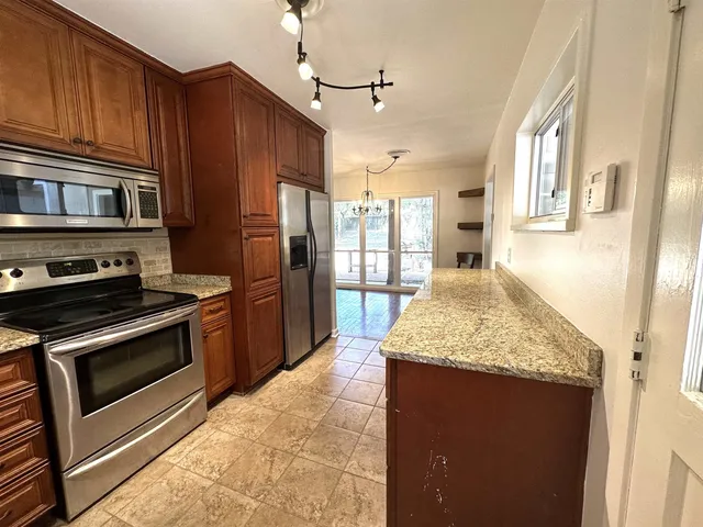 a kitchen with stainless steel appliances granite countertop wooden cabinets stove and granite counter top