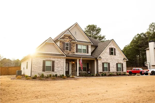 a view of a white house with a large tree with wooden fence