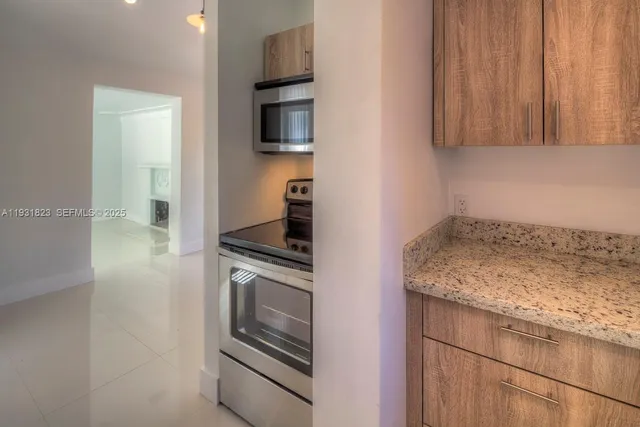 a kitchen with granite countertop a stove top oven microwave and cabinets