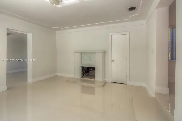 a view of an empty room with a fireplace and a window