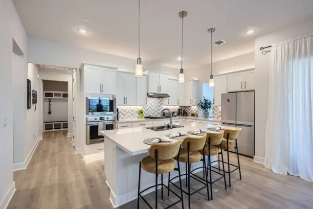 a kitchen with stainless steel appliances a dining table chairs stove and white cabinets