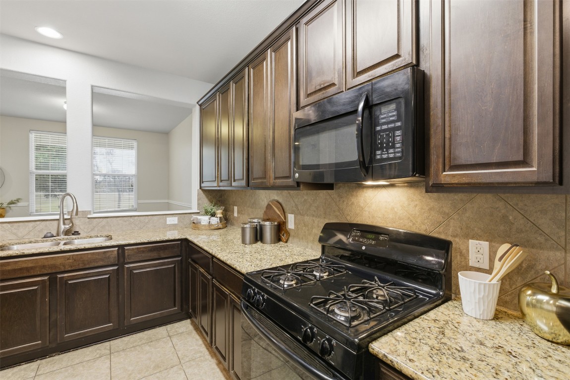 413 Shadow Point San Marcos, TX 78666 - Photo 9 of 34 Granite counters adorn the kitchen with a warm tile backsplash.