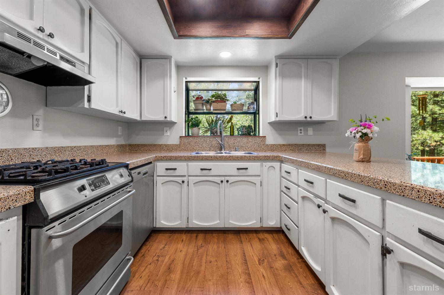 1121 Sundown Trail South Lake Tahoe, CA 96150 - Photo 13 of 40 a kitchen with granite countertop a stove a sink dishwasher and white cabinets with wooden floor