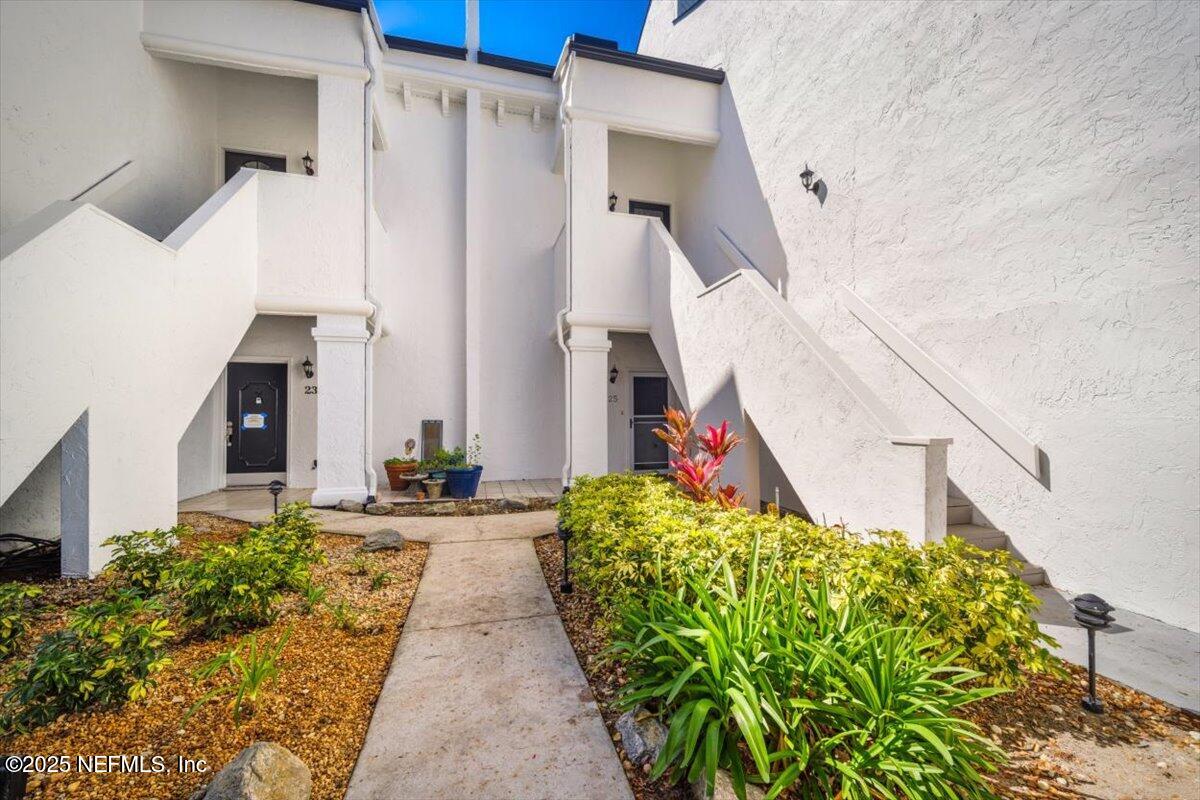 a view of a pathway of house with flower plants