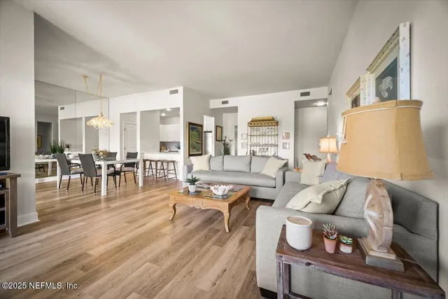 a living room with furniture kitchen view and a wooden floor