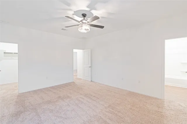 an empty room with a chandelier fan and windows