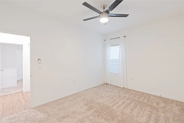 an empty room with a fan & a window