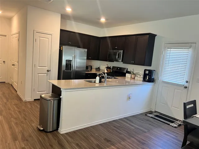 a kitchen with a sink a refrigerator and wooden floor