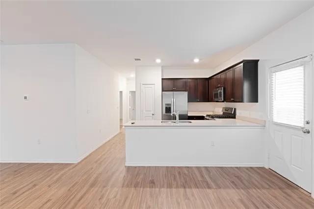 a large white kitchen with wooden floors and white stainless steel appliances