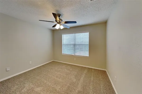 an empty room with a window and a fan