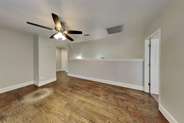 an empty room with wooden floor fan and windows