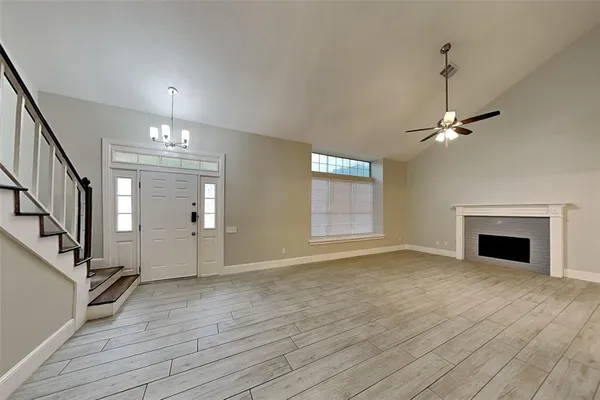 a view of an empty room with wooden floor fireplace and a window