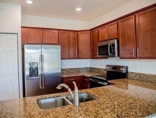 a kitchen with stainless steel appliances granite countertop a stove a sink and a microwave
