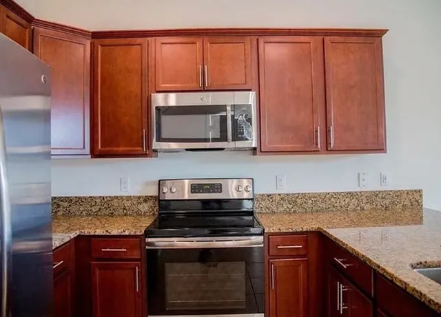 a kitchen with stainless steel appliances granite countertop a stove microwave and cabinets