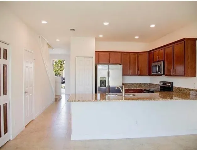 a kitchen with stainless steel appliances granite countertop a refrigerator and a sink