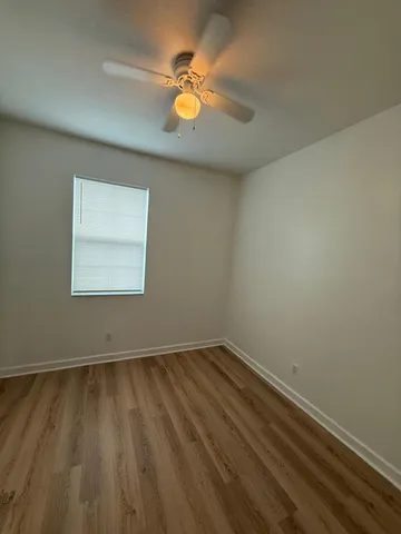 an empty room with a window and a ceiling fan