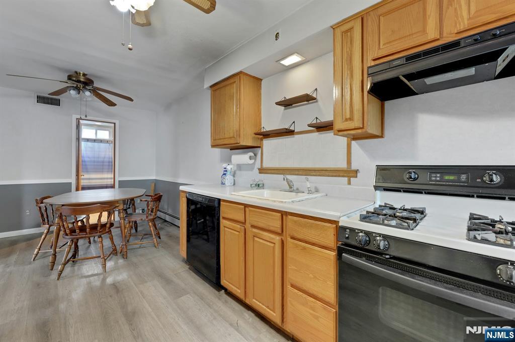 17 Butler Place Wanaque, NJ 07420 - Photo 14 of 28 a kitchen with stainless steel appliances granite countertop a stove a sink dishwasher and white cabinets with wooden floor