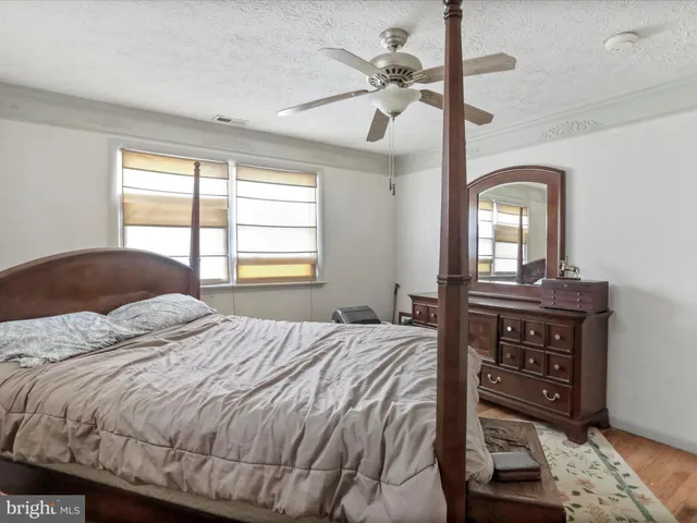 a bedroom with a bed a dresser with wooden floor