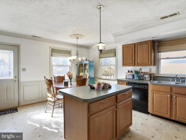 a kitchen with a stove a refrigerator a sink a dining table and chairs with wooden floor