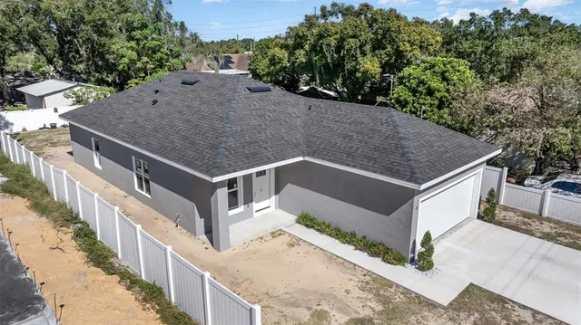 a view of a house with a small yard and large tree