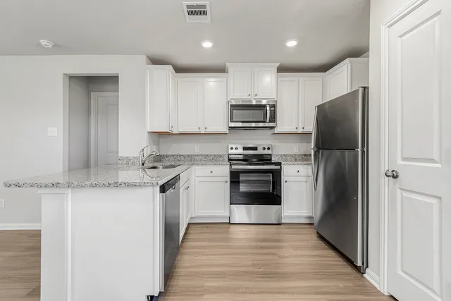 a view of a kitchen with a sink a refrigerator and wooden floor