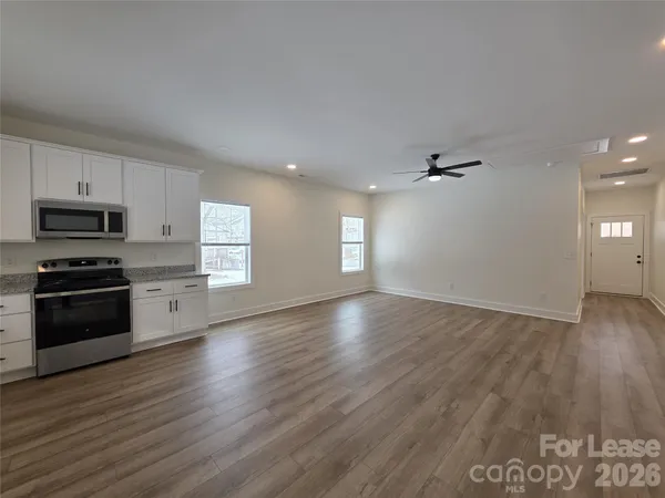 a view of kitchen with granite countertop wooden floors stainless steel appliances and sink