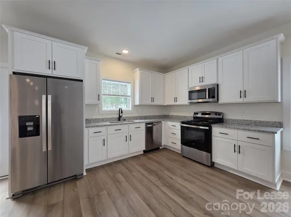 a kitchen with granite countertop white cabinets and stainless steel appliances