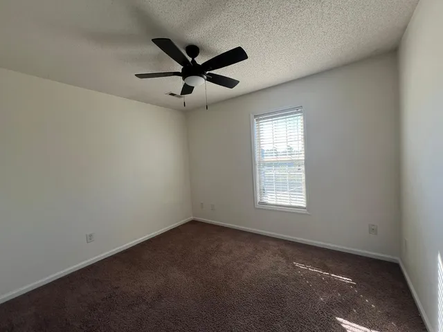 an empty room with a window and a fan