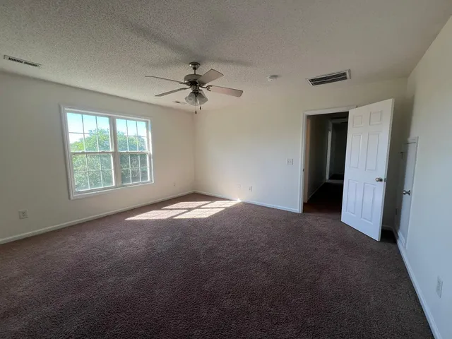 an empty room with windows and fan