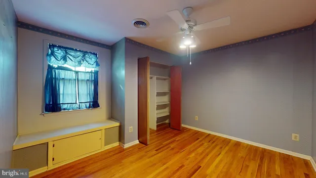 a view of an empty room with window and wooden floor