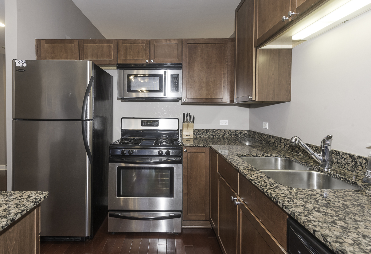 901 West Madison Street, Unit 818 Chicago, IL 60607 - Photo 13 of 26 a kitchen with kitchen island granite countertop a sink stove and refrigerator