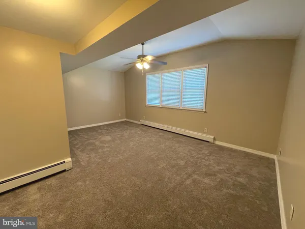 an empty room with a chandelier fan and windows