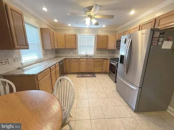 a kitchen with stainless steel appliances granite countertop a refrigerator a sink a stove a washer dryer and a dining table