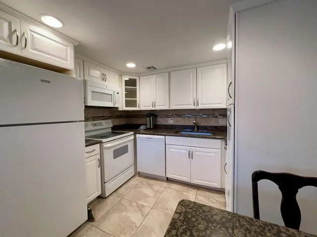 a kitchen with a refrigerator and white cabinets