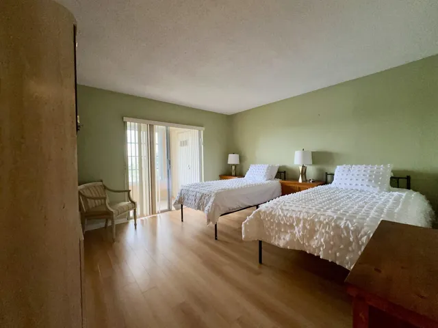 a bedroom with two beds and a potted plant next to a window
