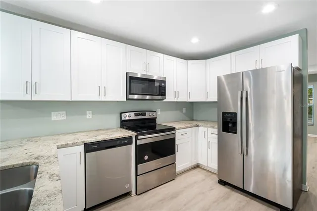a kitchen with stainless steel appliances white cabinets and a refrigerator