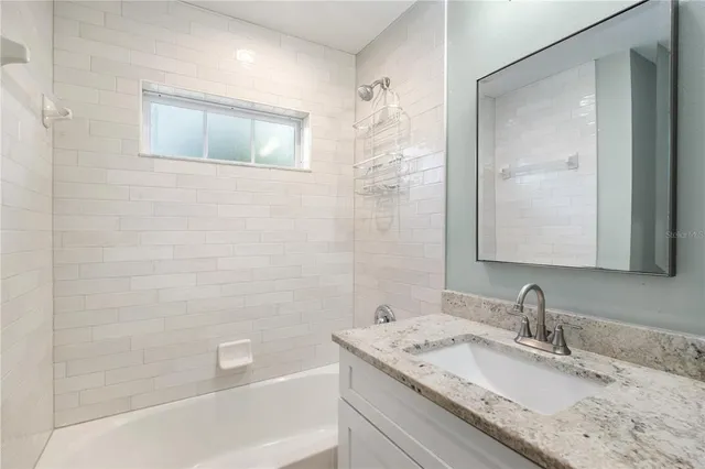 a bathroom with a granite countertop sink a mirror and a bathtub