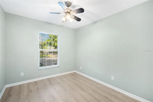 an empty room with a window and a fan