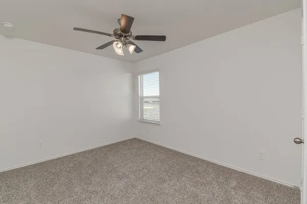 a view of an empty room and chandelier fan