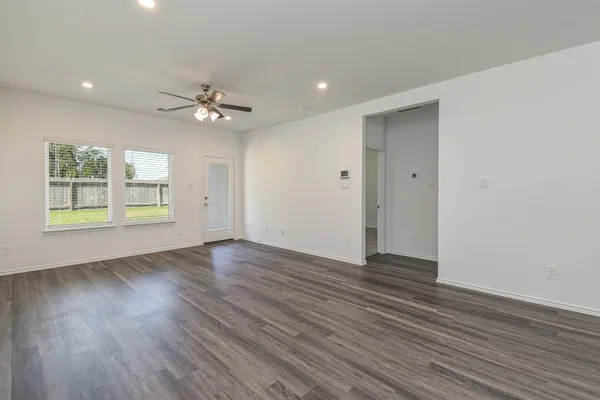 a view of an empty room with a window and wooden floor