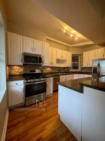 a kitchen with granite countertop a stove top oven and cabinets